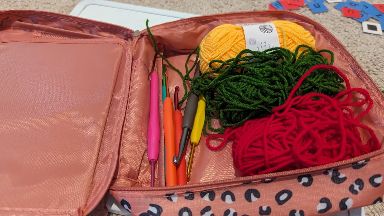 Yellow, Green, and Red yarn with several crochet hooks adjacent