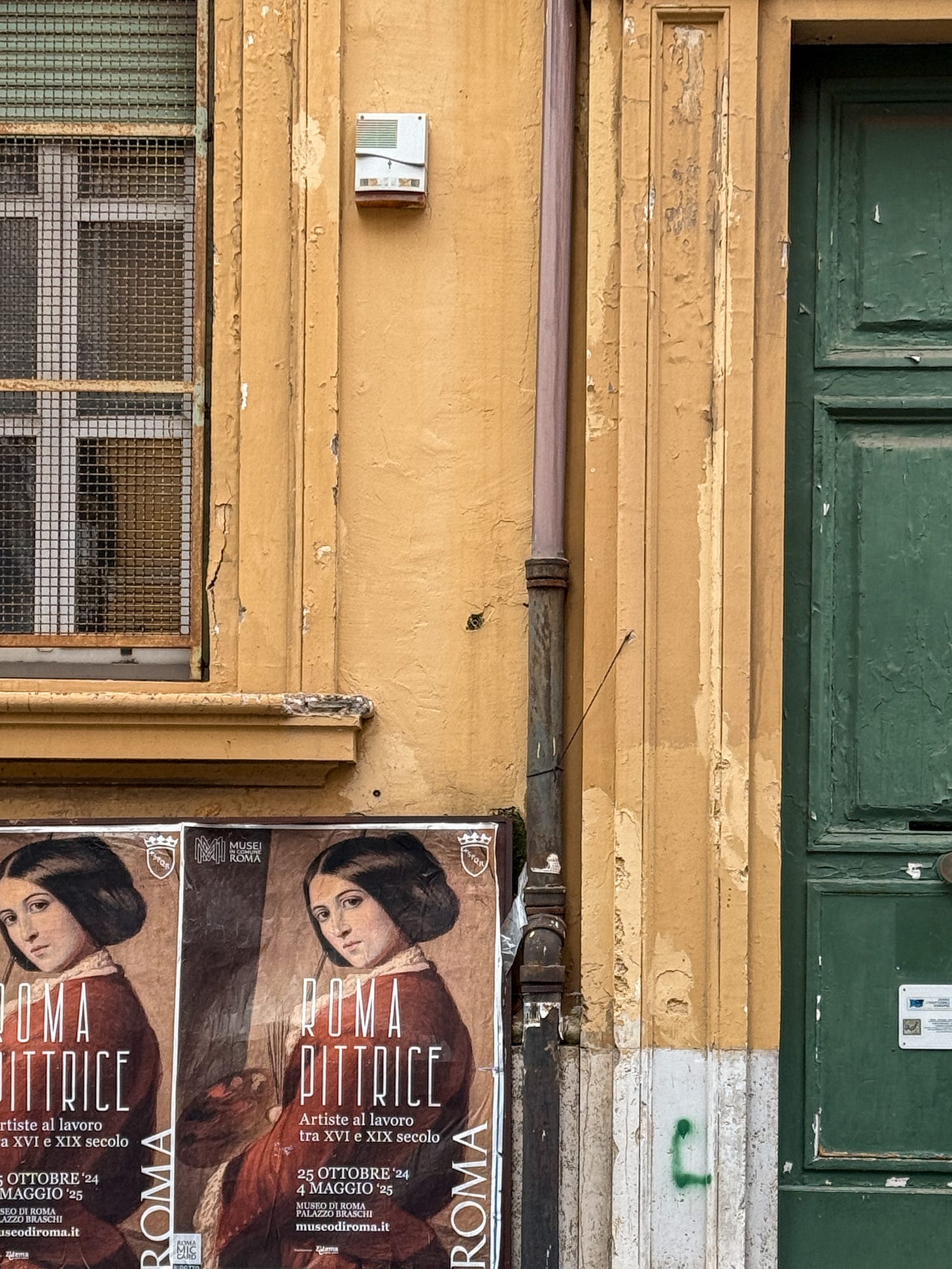Worn ochre wall with peeling paint, green door, and a pair of vintage-style posters advertising the "Roma Pittrice" exhibition at Museo di Roma, featuring a portrait of a 19th-century woman artist.