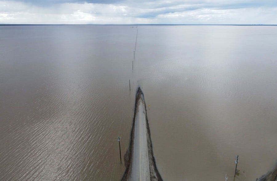 An aerial view of a road disappearing into a flooded plain