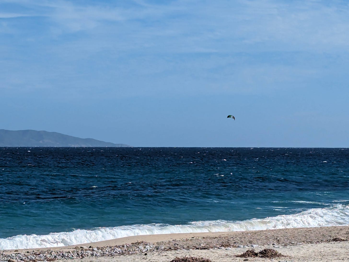 Kitesurfer from a distance on the blue water