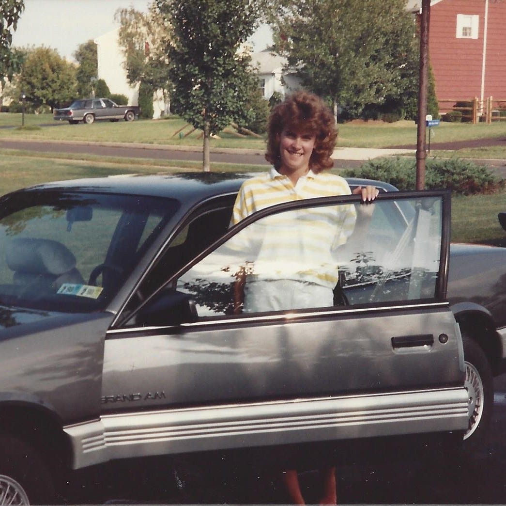 23-year-old woman standing by her sporty Grand Am coupe