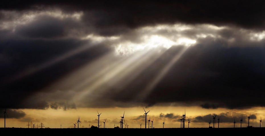 Sunbeams shine through clouds onto a field of wind turbines near Weissenfels, Germany. 