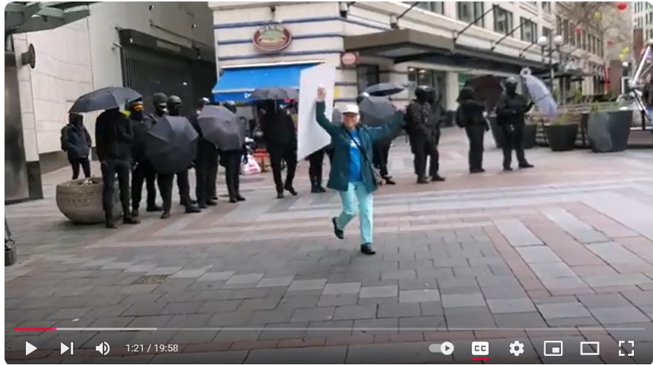 Medical Freedom fighter marches past Antifa.