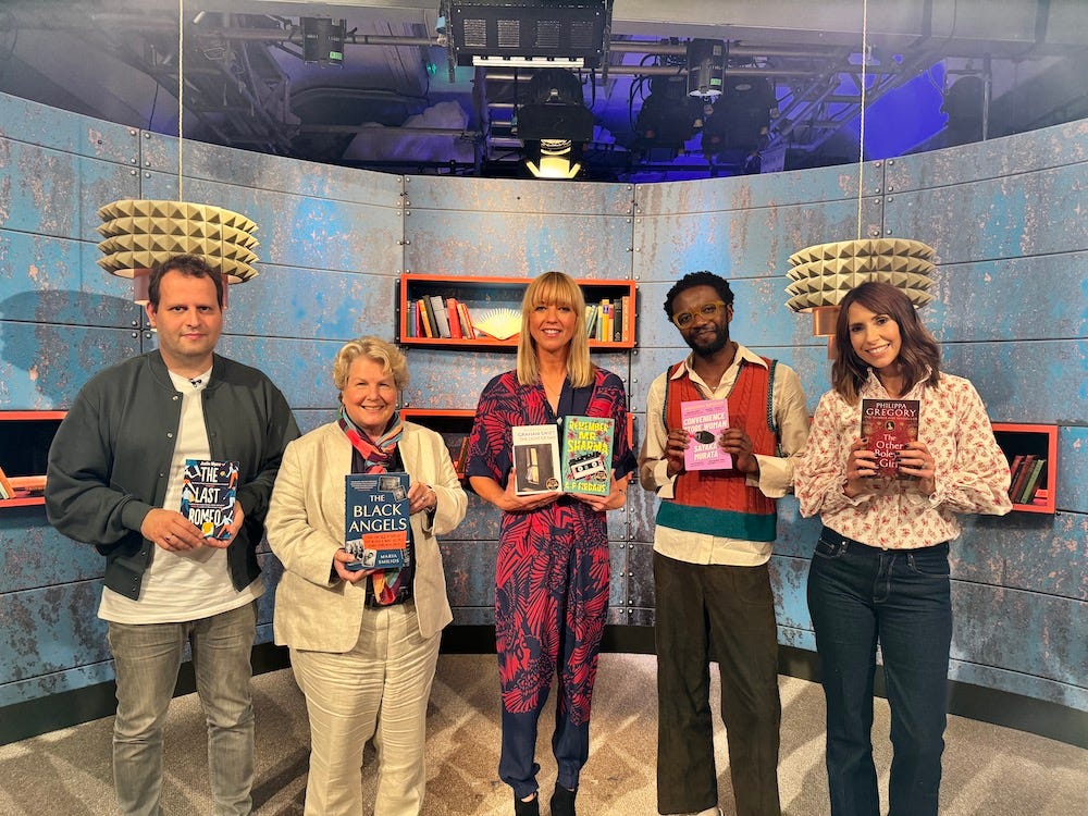 Adam Kay, Sandi Toksvig, Sara Cox, Omari Douglas and Alex Jones stand on the set of the BBC2 show between the covers, holding their chosen books