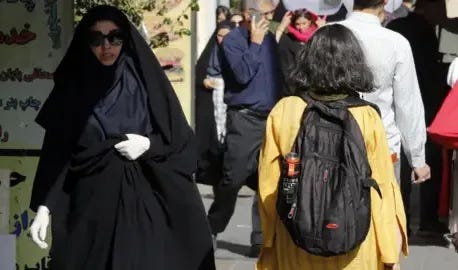 EPA A girl with her hair uncovered walks past a veiled woman on a street in Tehran, Iran (13 September 2023)