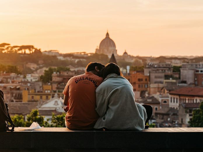 a couple of people sitting on top of a wooden bench