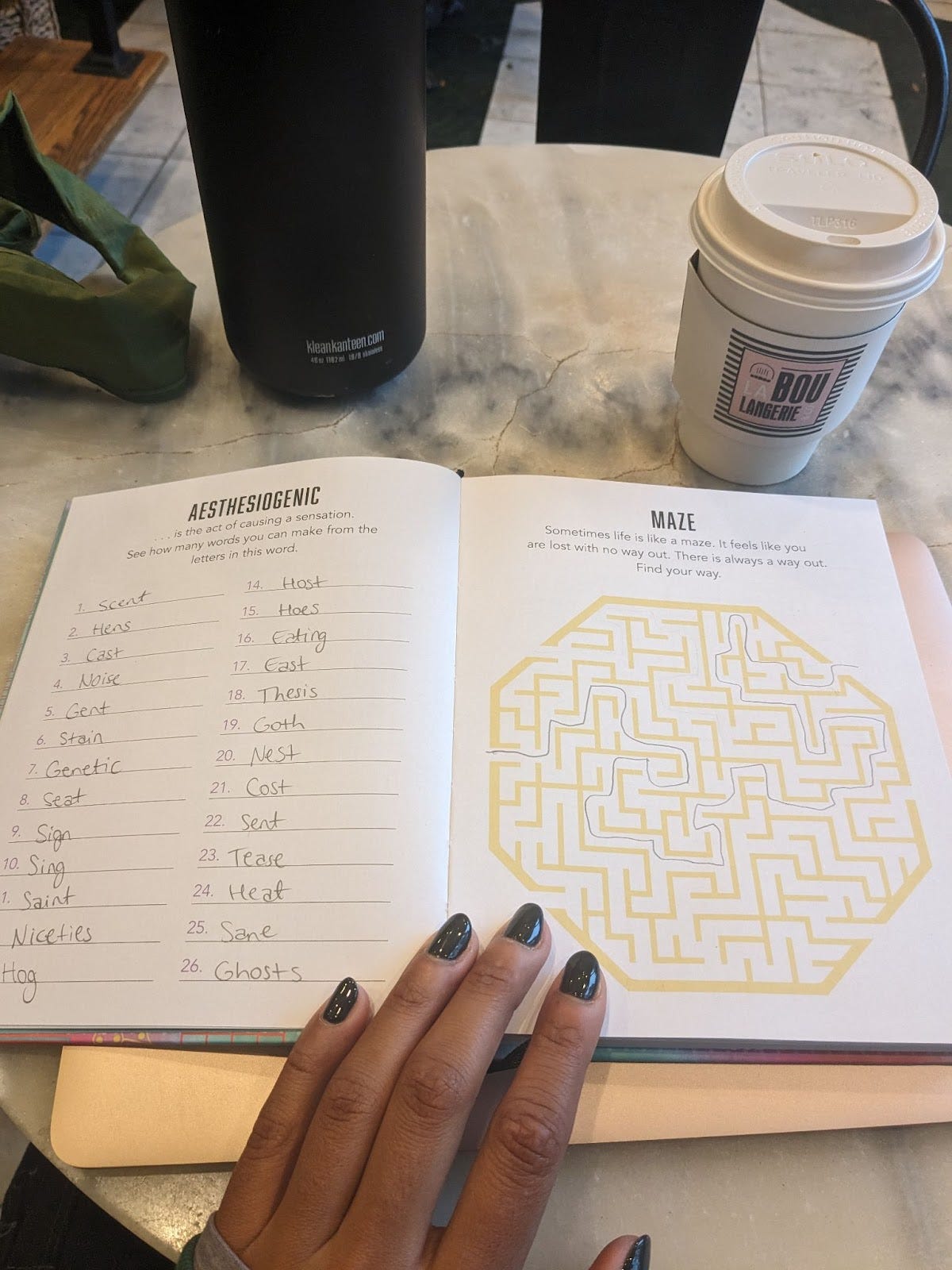 A book with the page turned to a word jumble page that Nathalie has filled out and the next page shows a yellow maze with pencil markings to shows how to escape the maze.
