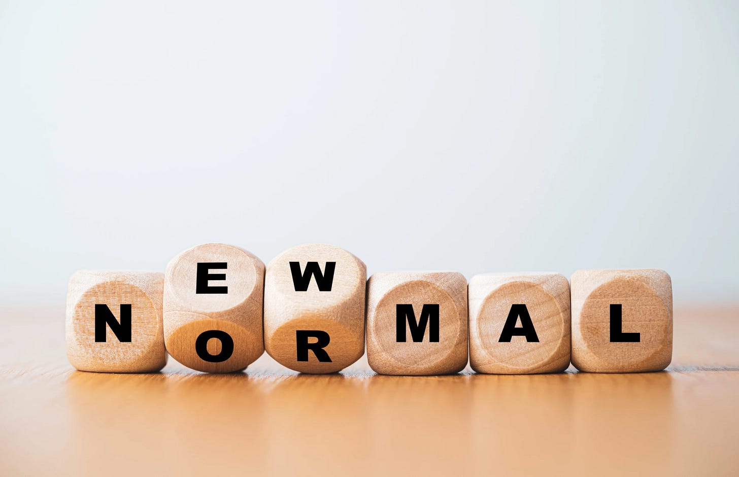 Wooden dice arranged to spell out "NEW NORMAL," symbolizing the adaptation to changing societal norms.