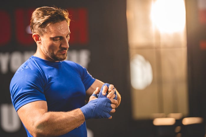 A muscular man wrapping his hands at the gym. A muscular man wrapping his hands at the gym.