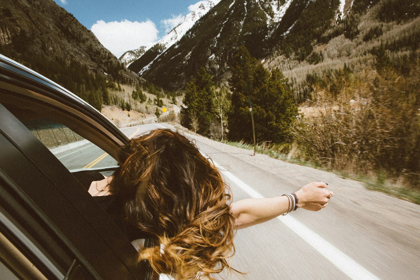 Woman riding in a car on a mountain road with the window open