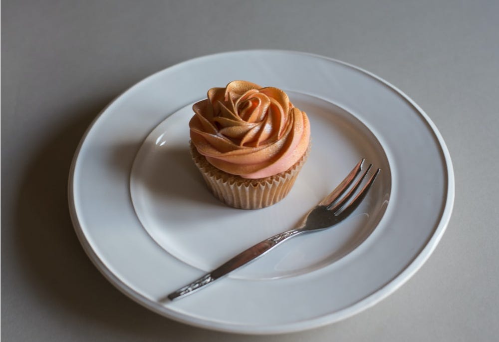 cupcake on a plate with a small fork - grey background