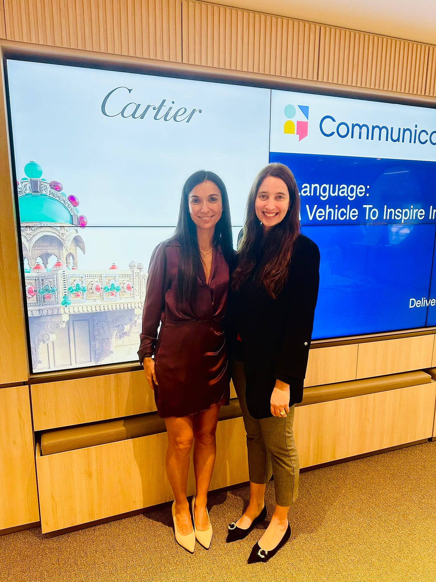 Picture of 2 women standing in front of a power point screen with a sign that reads CARTIER