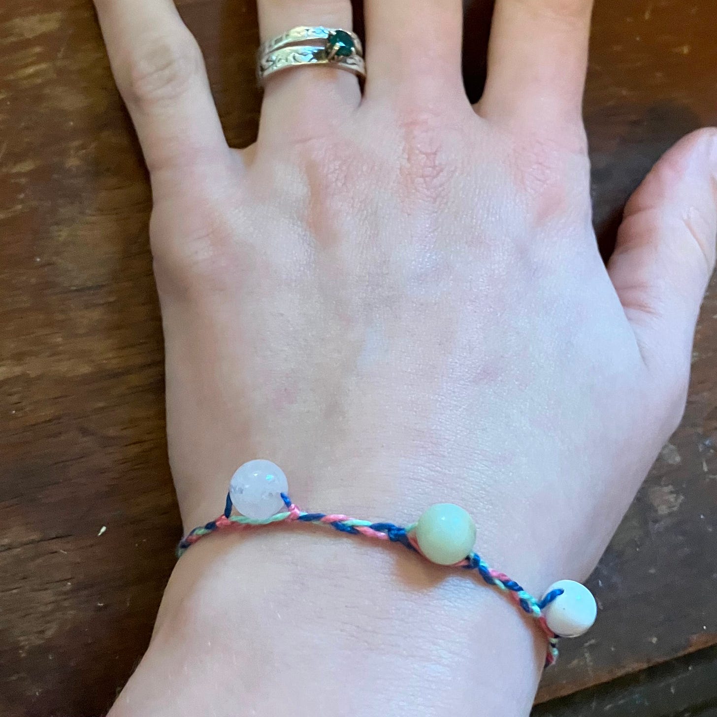 A photo of a hand with a simple braided bracelet with three beads integrated into it on the wrist.