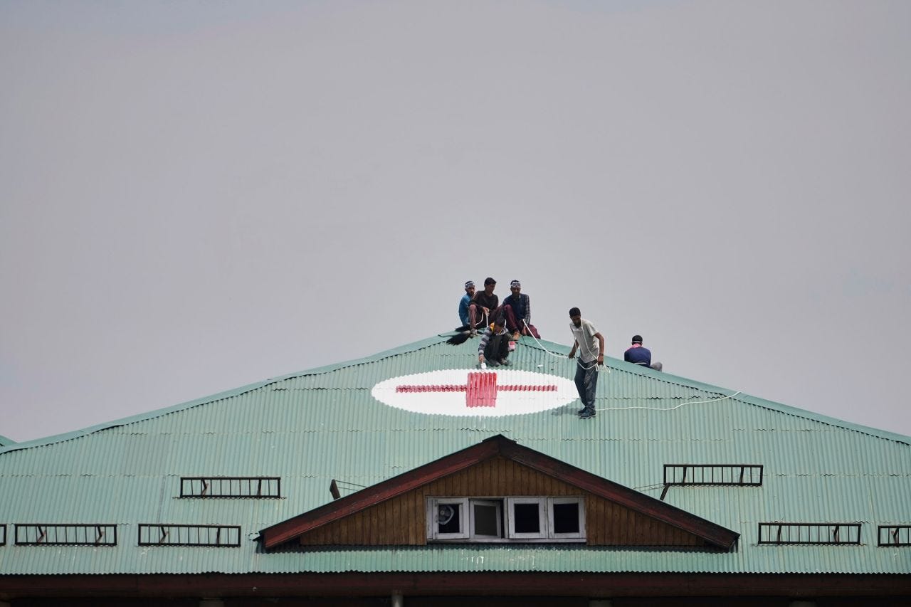 Workers paint a red and white medical emblem on the roof of a hospital on the outskirts of Srinagar, India-administered Kashmir.