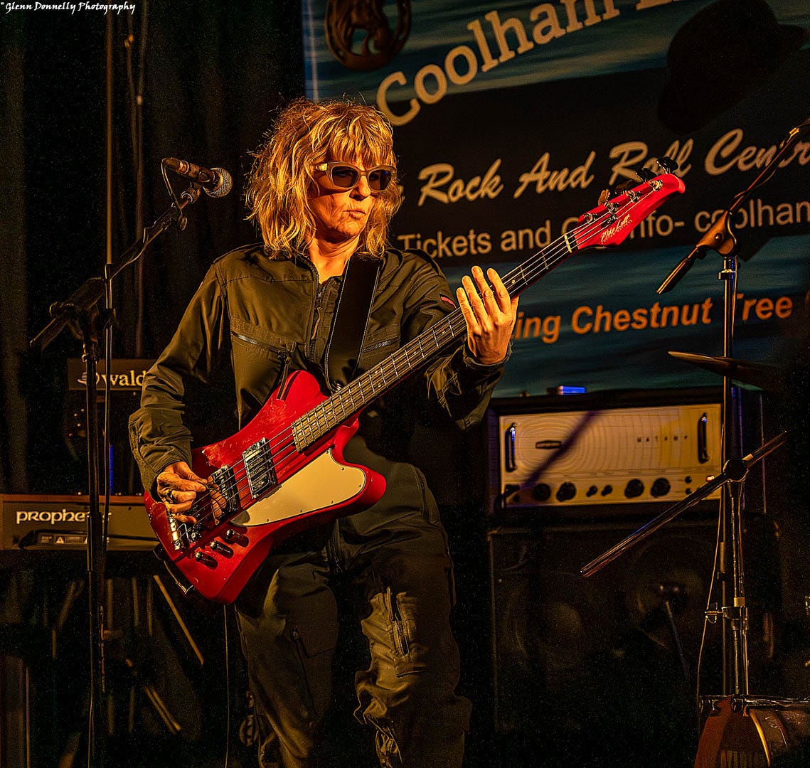 Suzy Starlite playing a big red bass guitar 