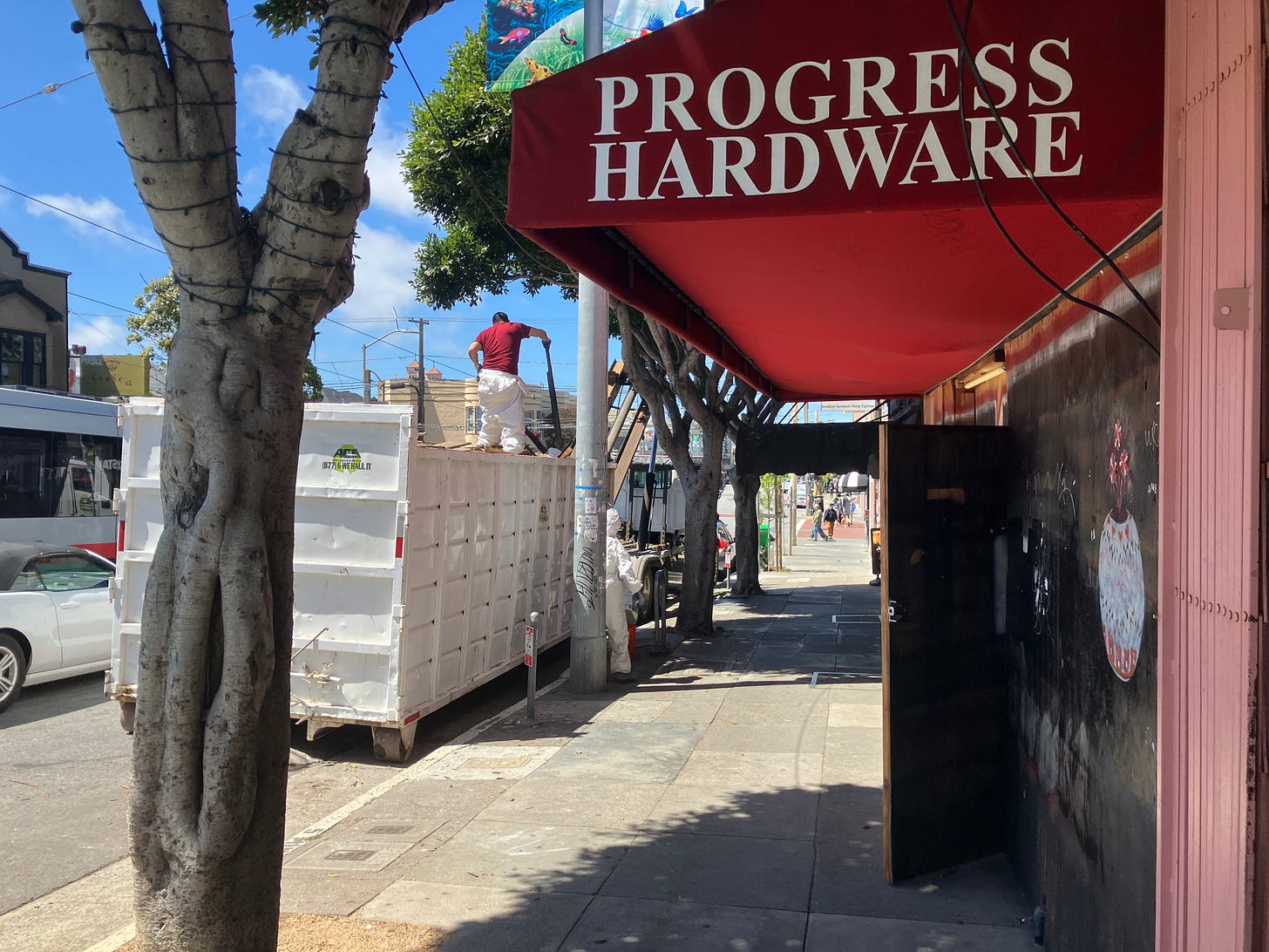 image of progress hardware store in SF from the outside, with the awning visisble. a debris box is in front of the store where workers are taking things in and out of the store