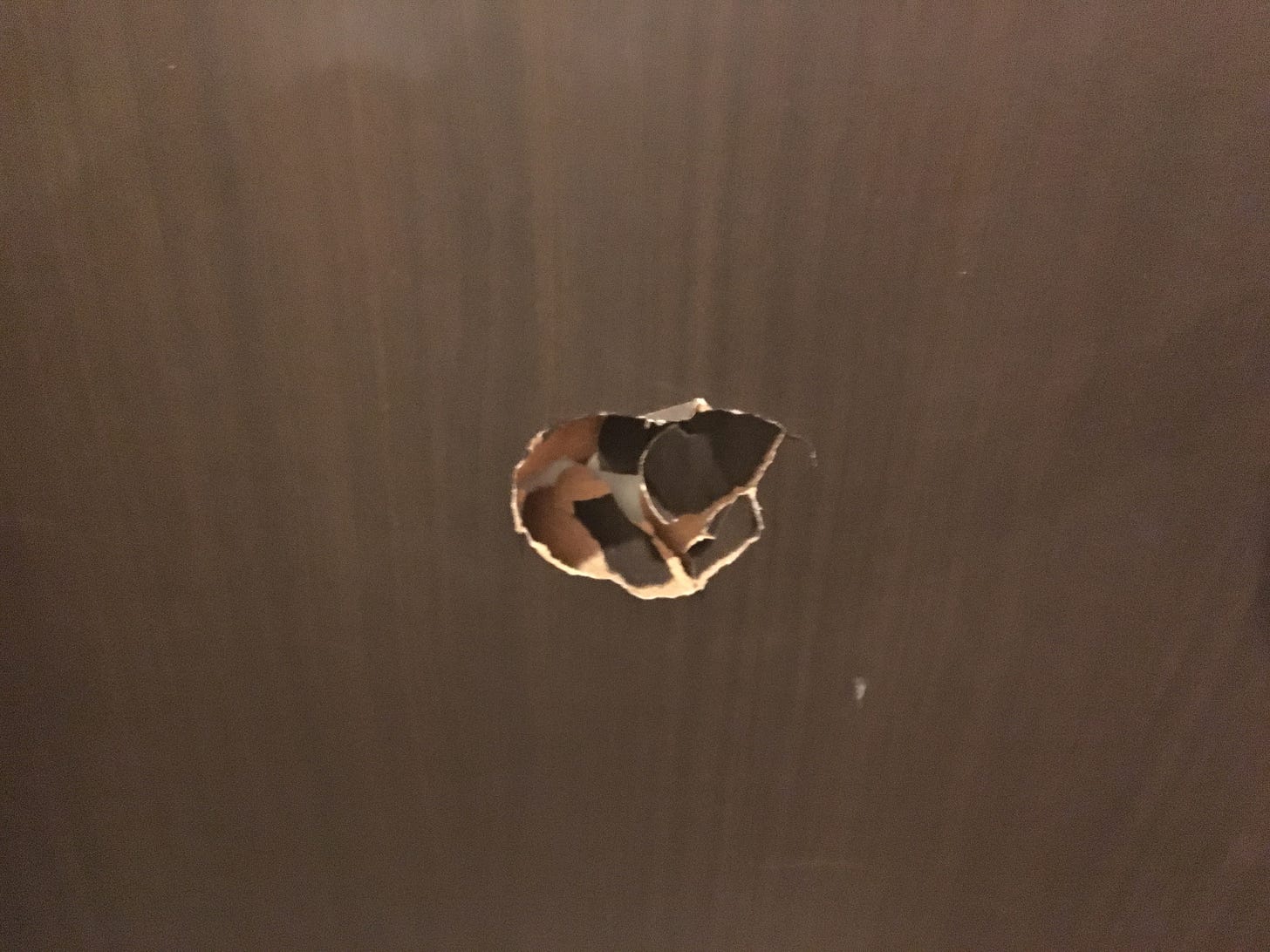 A hole in the door of the hotel room. 