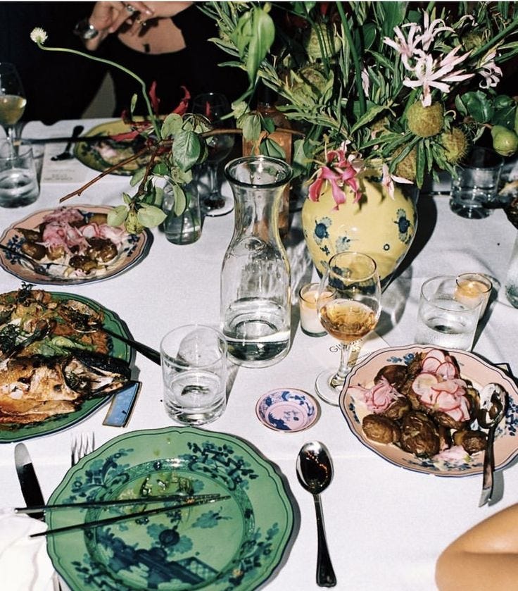 This may contain: the table is set with plates, silverware and vases filled with flowers on it