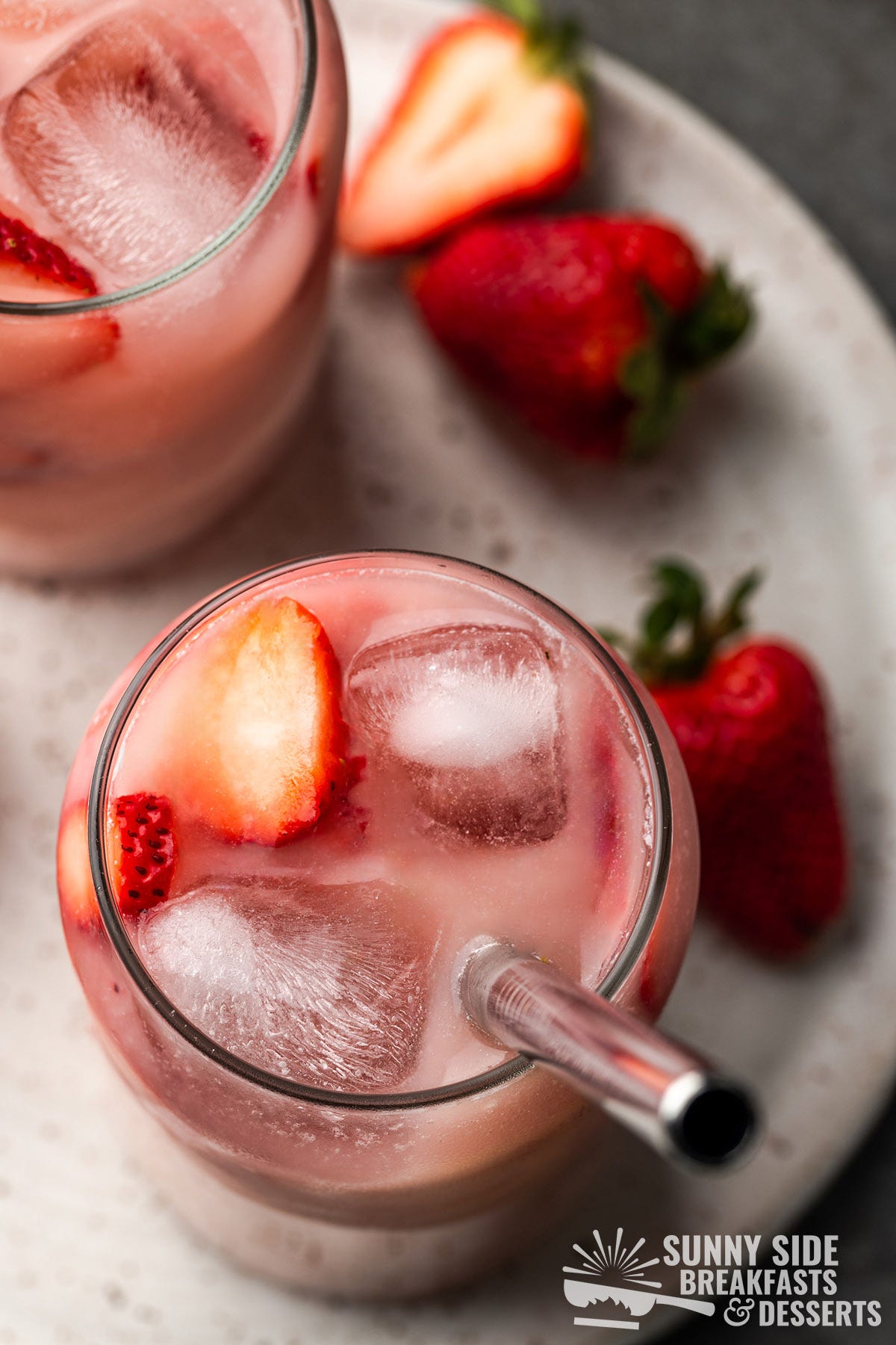 Pink drink with ice and fresh strawberries.