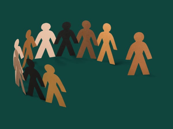 Chain of paper people in different shades of brown, with one cut off from the group, against a green background
