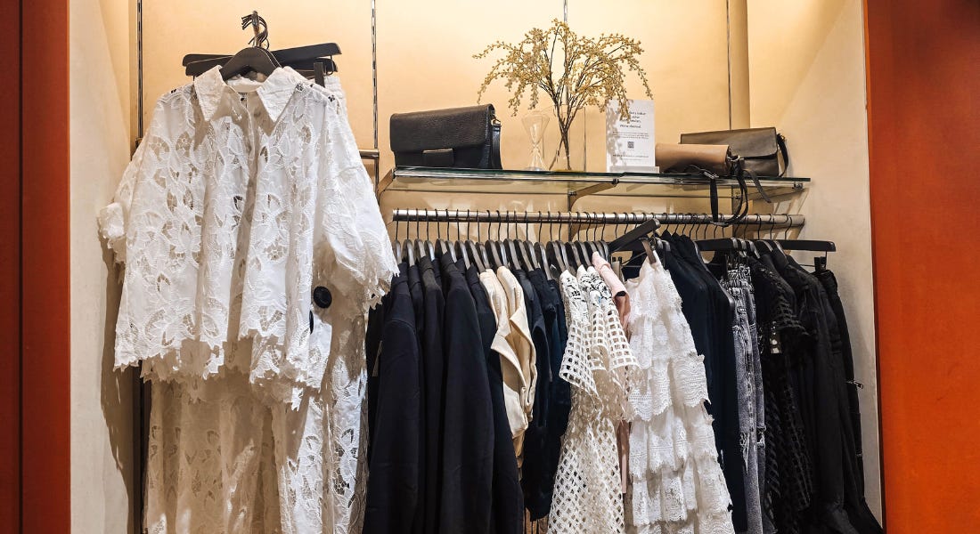 A white clothes shop wall with white lace and black garments hanging from the rail