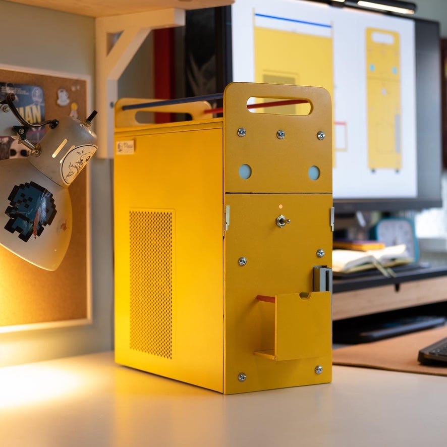 Photo of the finished computer project. It's a yellow PC tower that looks like a robot. It's got blue eyes, handles on top and big shiny bolts.