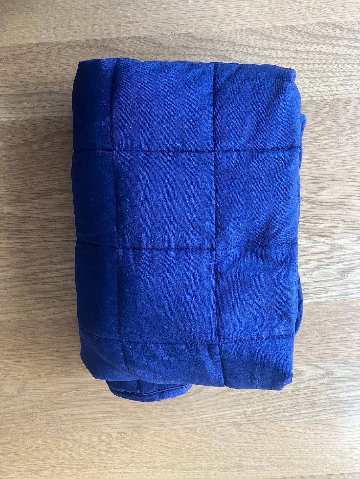 Blue folded blanket on a wood table.