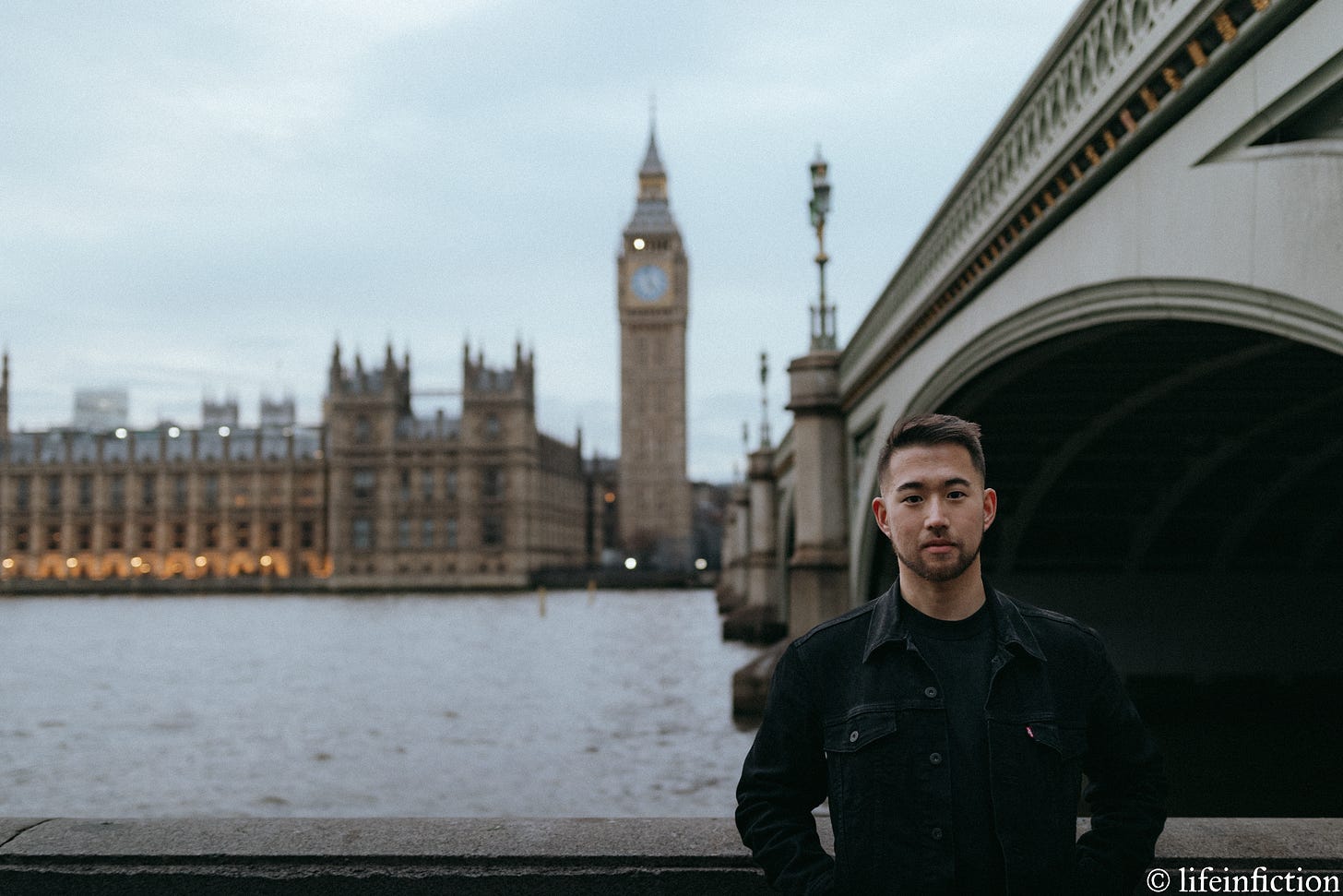 DJ, with a serious expression, standing to the right of the frame against a stone railing with Westminster Bridge behind him with Big Ben and Westminster Abbey in the background across the Thames.