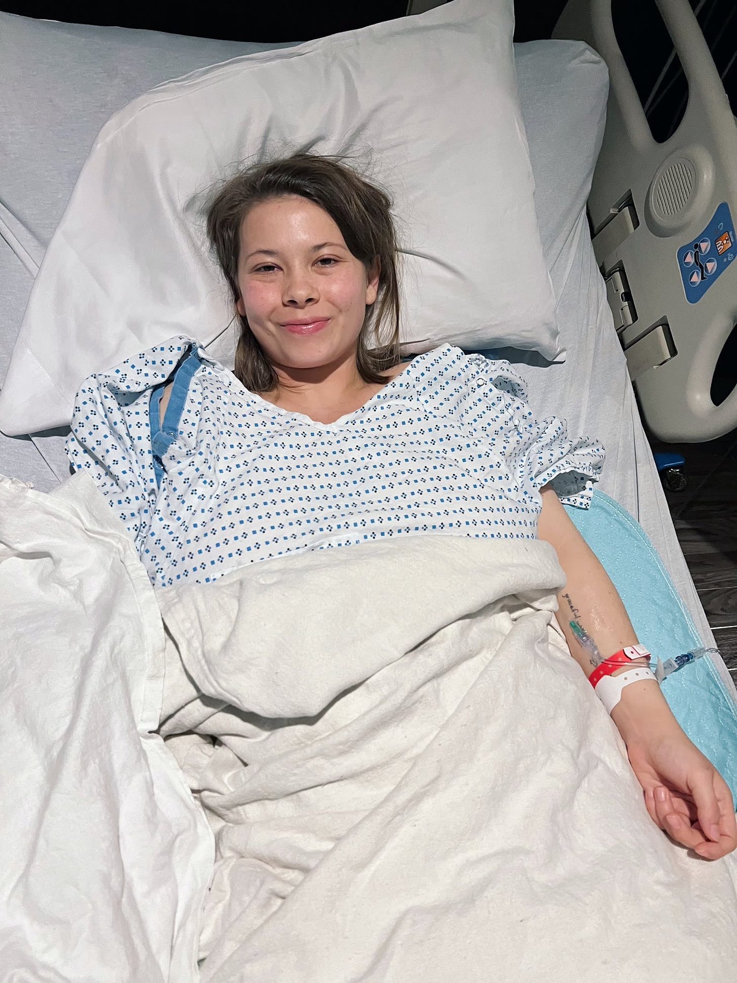 Bindi Irwin - a white Austrailian - lays down in a hospital bed 