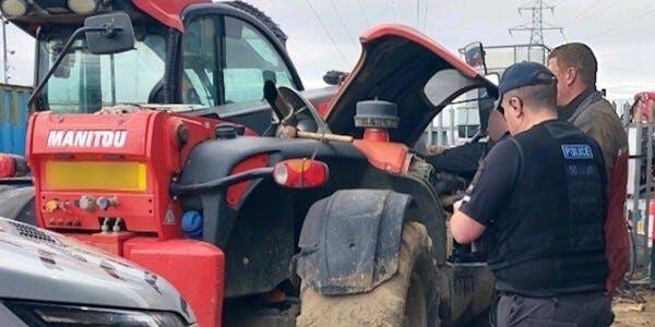 An officer from the Essex Police Rural Engagement Team inspecting a red tractor's engine at Harwich Port