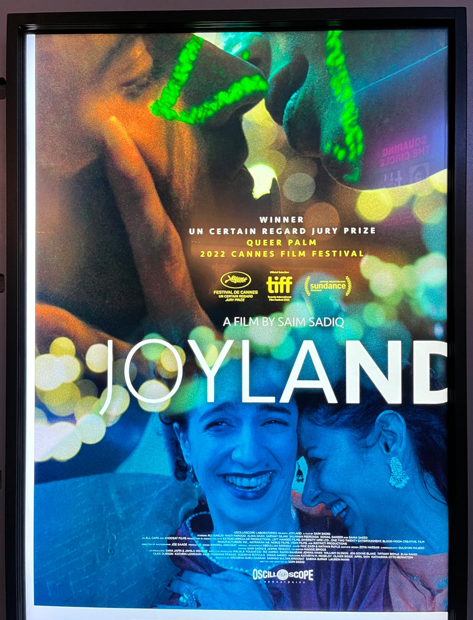 Joyland movie poster. At the top, a close-up of two faces about to kiss. At the bottom, two women laugh together.