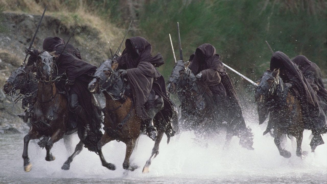 The Black Riders ride their horses through the river