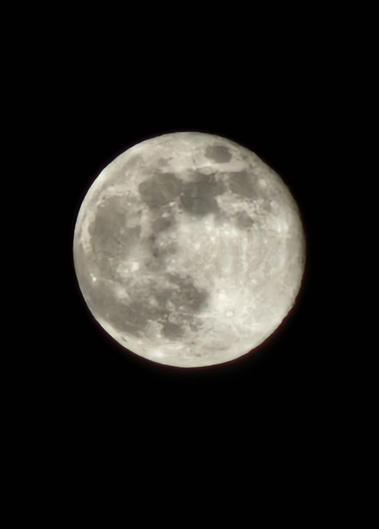 Image description: The full moon of the 27th of December, centred in the photo and surrounded by darkness. A lot of detail is visible on the moon despite it being a phone photo.