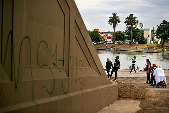Gang-related graffiti mark territory in L.A.’s MacArthur Park. In 2020, LAPD Chief Michel Moore banned his officers from accessing a statewide gang database, impeding their ability to locate gang associates of shooting and homicide suspects. (JASON ARMOND/LOS ANGELES TIMES/GETTY IMAGES)
