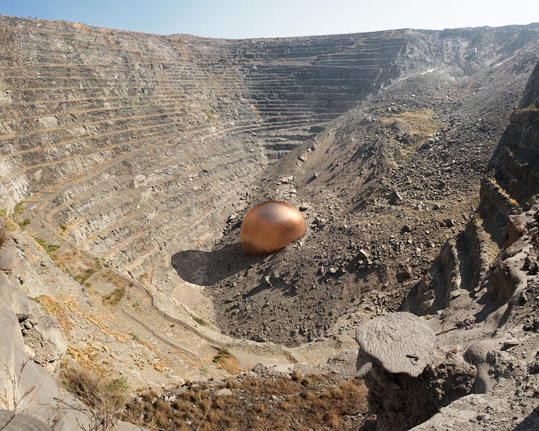 This is a photo of a dig, with a CGI ball of copper in the middle, which is roughly 1/100th of the size of the dig. Made by Dillon Marsh, it's to communicate the size of the impact on the landscape compared to what's actually used.