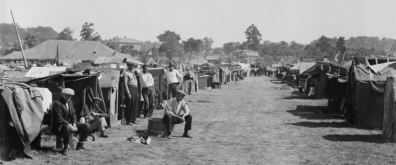 Men sit in front of a row of shanties.