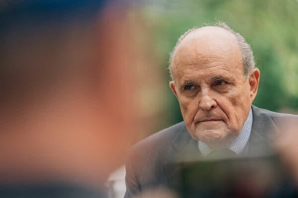 Rudolph W. Giuliani staring ahead during a news conference in a park.