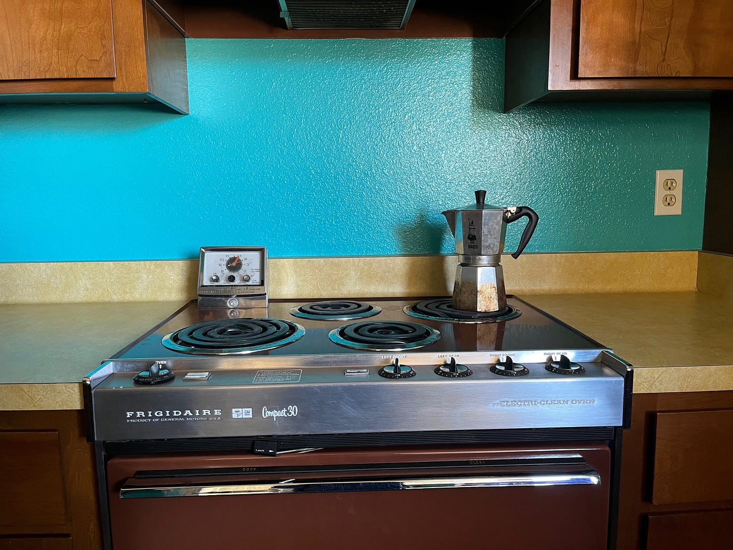 the stove in my old kitchen, with a moka pot on the back burner and turquoise walls