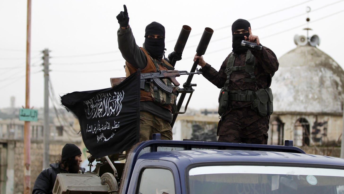 Al-Nusra Front fighters ride on a pick-up truck carrying an anti-aircraft gun in Idlib province, north-western Syria (2 December 2014)