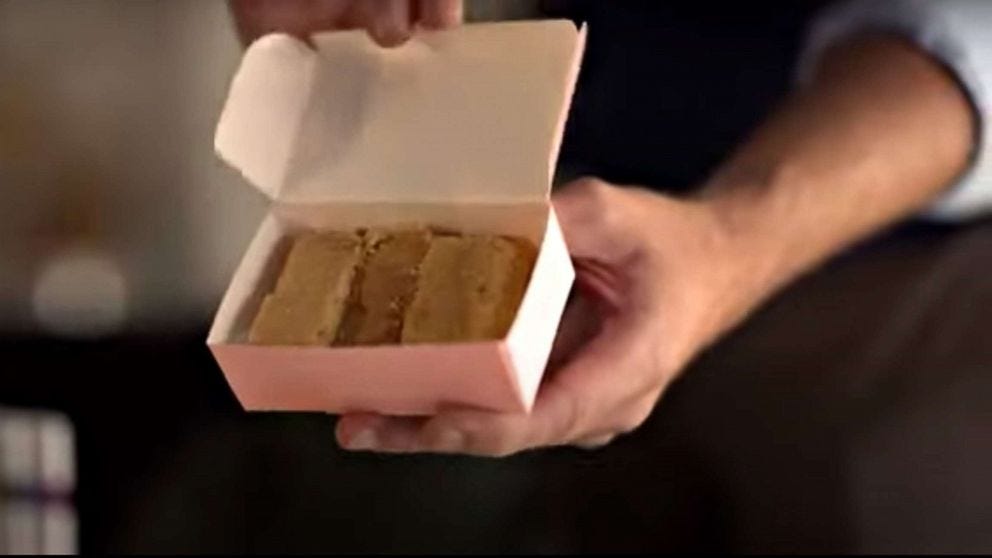 Ted Lasso's hands holding a box full of biscuits