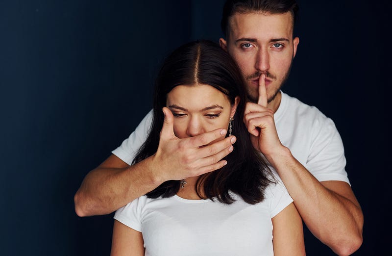 Man holding hand over woman's mouth to silence her Man holding hand over woman's mouth to silence her