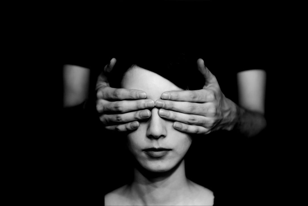 person covering the eyes of woman on dark room