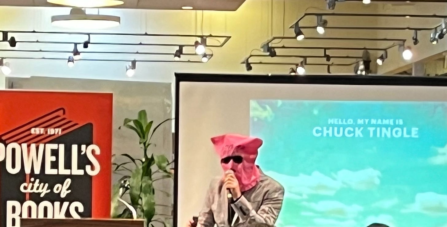 Chuck Tingle at Powell's City of Books, wearing a tan-and-pink plaid suit, a pink mask, and sunglasses