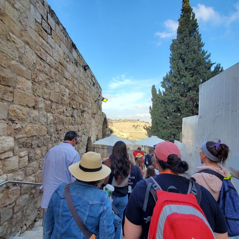 A group of tourists walks along a narrow passageway in Jerusalem's old city.