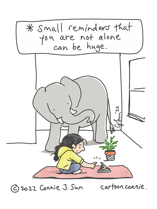 Small Reminders Single-panel comic of a girl with a braid at home, seated on a yoga mat, connecting with a friend on the phone. This is represented by a hand reaching out from a phone screen, index finger extended. The girl meets the hand halfway, fingertips about connect. Elephant looks on in the background. Caption reads, "Small reminders that you are not alone can be huge." Original cartoon illustration by Connie Sun, cartoonconnie, 2022