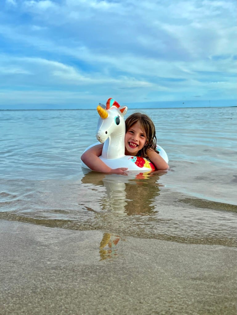 A child in a unicorn float on a beach

Description automatically generated