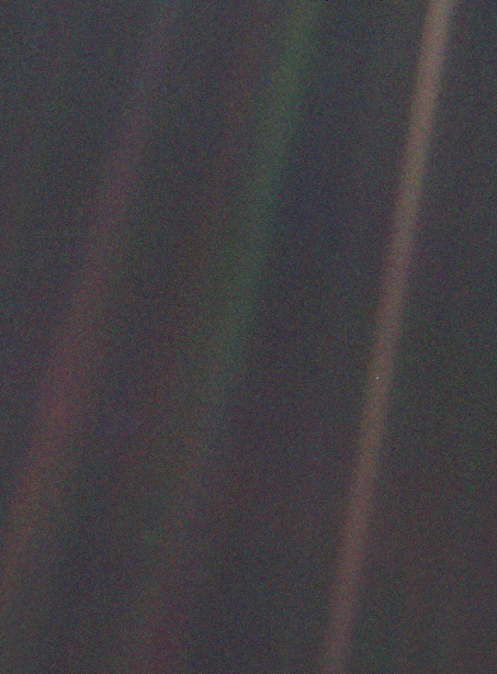 A photo of Earth as seen from the Voyager space probe, roughly 6 billion kilometres away. Earth appears as a tiny blue dot suspended in a greenish-red ray of light.