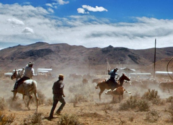 a group of men riding horses through a desert