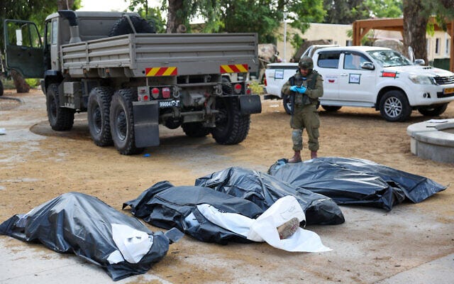 An IDF soldier prepares to remove the bodies of Israelis killed during an October 7, 2023, attack by Palestinian terrorists, in Kibbutz Kfar Aza, in southern Israel bordering the Gaza Strip, on October 10, 2023. (JACK GUEZ / AFP)