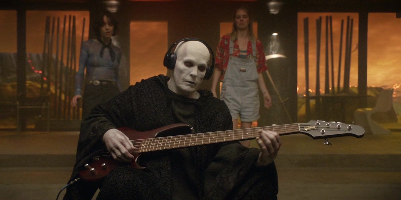 Death plays a 5-string bass guitar with headphones on in Bill & Ted Face the Music.